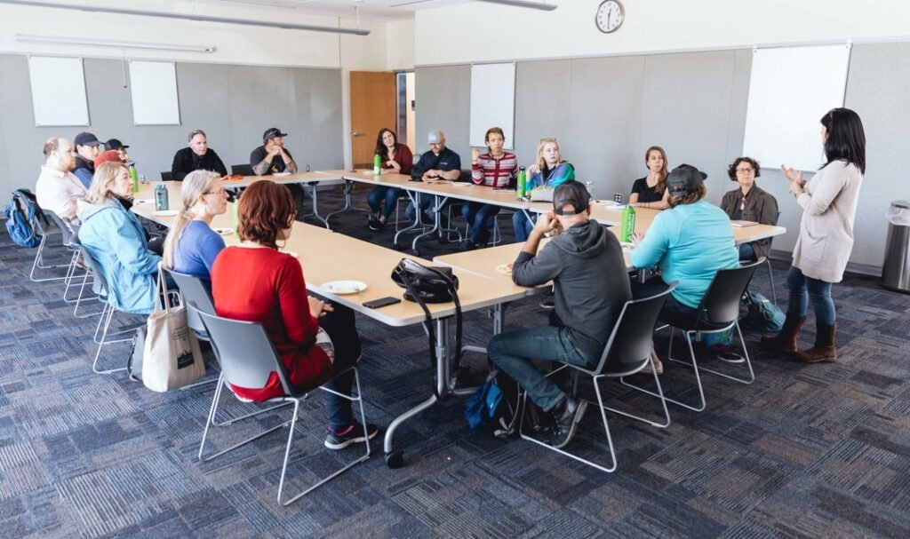 Group of people around a square setup of meeting tables.