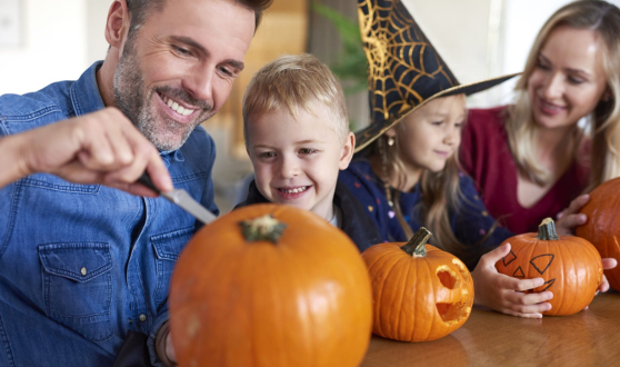 Family together painting and decorating Halloween pumpkins.